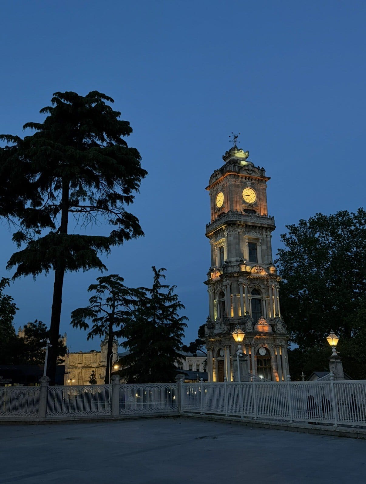Beleuchteter Uhrturm des Dolmabahçe-Palasts bei Abenddämmerung